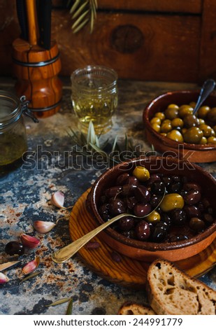Mixed marinated olives (green, black and purple) in two ceramic plate on old metal table. and vintage kitchen accessories. Rustic style