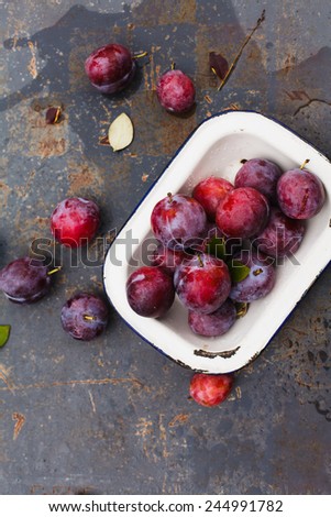 Fresh plums on a metal old plate. Healthy food from garden. Food blue background.