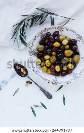 Mixed marinated olives (green, black and purple) in two ceramic plate on a marble table. Rustic style.