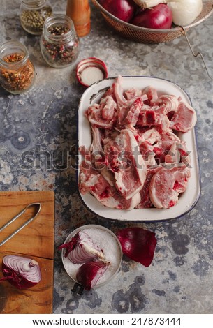 Raw fresh Lamb Meat ribs on old  metal bowl  with vintage kitchen accessories  on old  metal background. Natural meal concept.