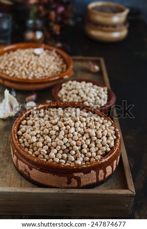 Still life of three types chickpeas against a old wooden surface with fresh garlic and vintage  kitchen accessories in a country kitchen. Concept image for healthy or vegetarian cooking.