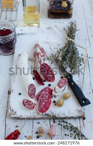 Cold meat plate of salchichon sausages served with red hot peppers on white wooden cutting board. See series. Natural meat concept. Spanish tapas