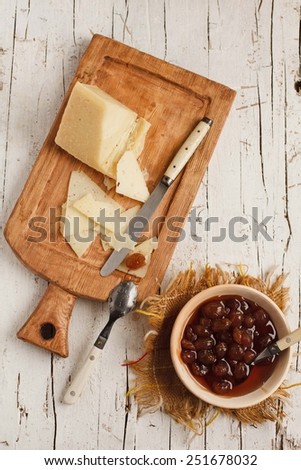 Antipasti pickled  cheese, and  grape marmalade  served on cast-iron board over wooden table with vintage fork. Food background. Fresh ingredients on a wooden table. Top view