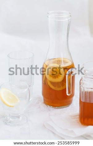 Glasses of Cold Iced tea with lemon and red drink . Drink  is served on a white rustic table. Natural drink concept.