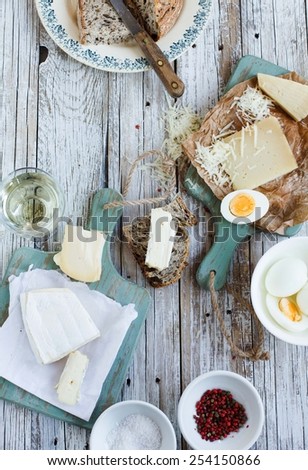 Still life of a antipasto of toast with two types cheese on a rustic table with whole grain bread. Meal is served on a table with boiled eggs. Authentic natural food.