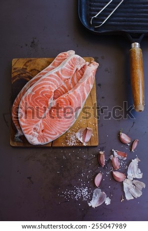 Freshly salmon fish stakes onto a vintage wood table with garlic slice and grill on a  metal background. Concept image for healthy, or vegetarian cooking. Top view. See series.