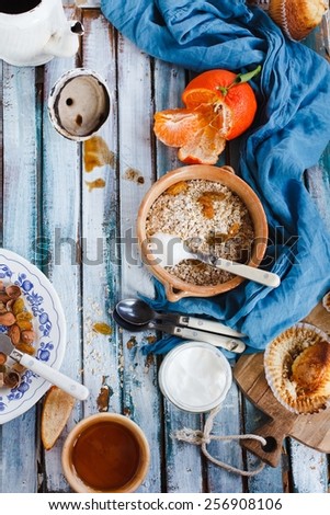 Breakfast table with whole oat flakes, nuts, honey and natural yogurt on a vintage blue wooden table. Concept image for healthy or vegetarian cooking.Natural fruit of garden Rustic style