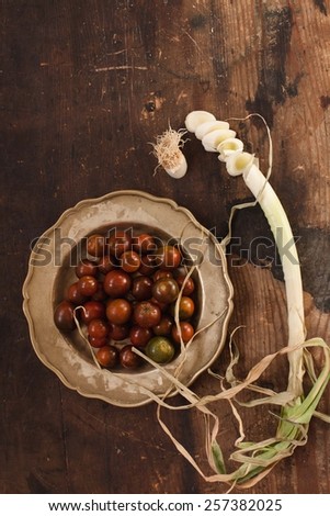Still life with colorful freshly tomatoes and onion  in vintage metal bowl, taken from vintage wood surface. Natural food concept. Top view