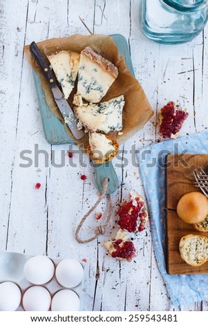 Table with blue cheese and slices of pomegranate over on vintage white wooden surface. Natural and healthy food concept. Fresh ingredients on a wooden table. Rustic style. Top view.