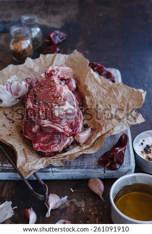 Raw fresh meat steaks  and seasoning over vintage wood table taken on dark metal background. Natural and country food concept.