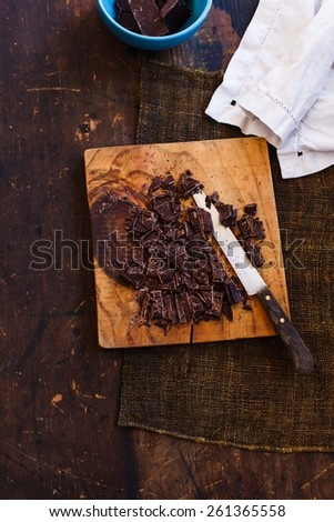 Slices of chocolate over on vintage table with knife, taken on dark table with linen napkin. Step on step recipe biscuit cake with chocolate. Rustic style. Top view.