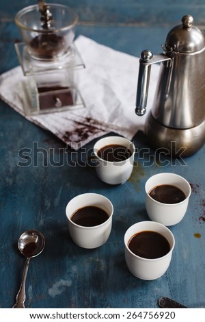Black natural Coffee on white cups with coffeemaker taken on a blue vintage table. Rustic style. Low key.