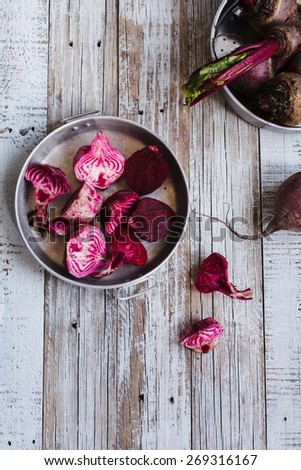 Colorful Red beets in two rustic bowl with knife over on white wooden table. Rustic style.Top view.
