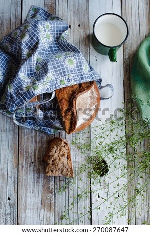 Fresh grain bread with cup of milk over rustic white table. Rustic style. Top view.