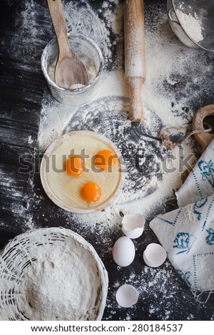 Baking cake or cupcakes ingredients - bowl, flour, eggs, egg whites foam and eggshells on black chalkboard from above. Cooking course or kitchen mess poster concept.