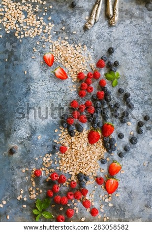Mix of Fresh ripe berries , blueberry, raspberry and cereals scattered of the blue table. Breakfast food concept. Rustic style.