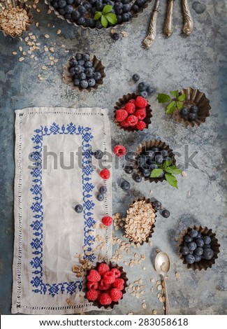 Breakfast cereals with summer berries raspberry, blueberry in vintage metal molds and decorative linen. beautiful rustic decorative scene from above.