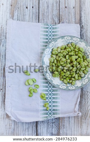 Young shelled fava beans in rustic plate on vintage linen cloth. Rustic style