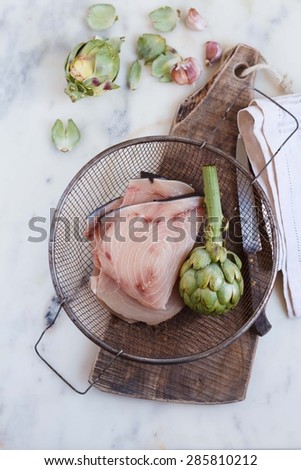 Swordfish with artichoke for dinner party. healthy, diet and cooking concept.  Rustic image from above.