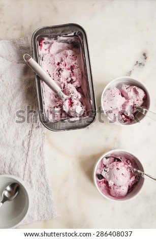 Vanilla ice cream with fresh fruits in blue bake mold  on marble background from above with rustic linen napkin.