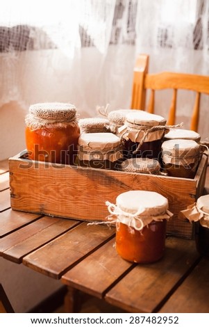 Organic homemade jam of many jars lined up on a rustic wooden kitchen table. Country styling image.