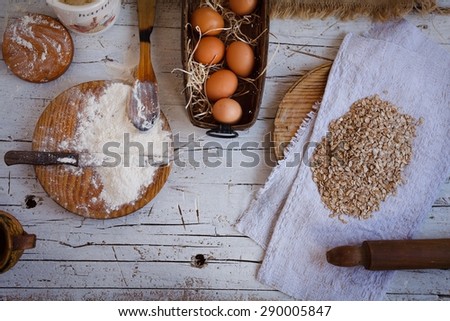 Baking ingredients in the kitchen with a bowl of eggs, free gluten flour, oat flakes, sugar, jug of milk and butter ready to bake a cake or make batter