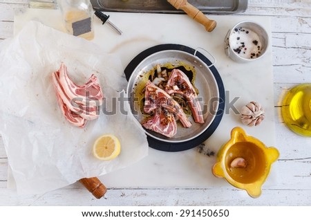 UNcooked marinade meat ribs on the metallic plate over marble table from above. Food preparation in rustic kitchen.