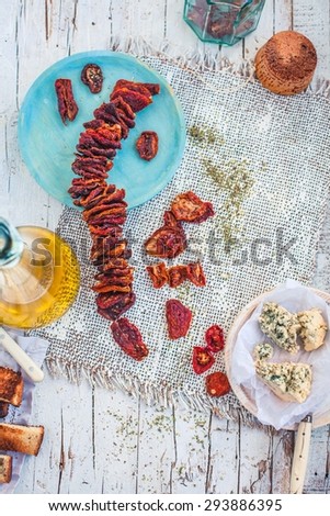 Traditional sundried tomatoes with bottle olive oil and blue cheese from above. Mediterranean food concept. Rustic style