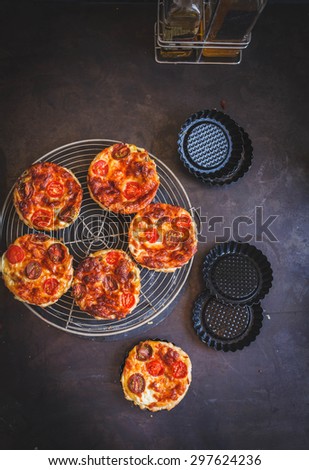 Homemade and vegetarian food concept. Mini tart, quiche with mozzarella cheese, mushroom and tomatoes cherry from above on a metallic dark table. Rustic image with natural light.