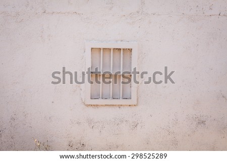 White grunge rustic wall with small white window in center . Vintage white wall with small window.