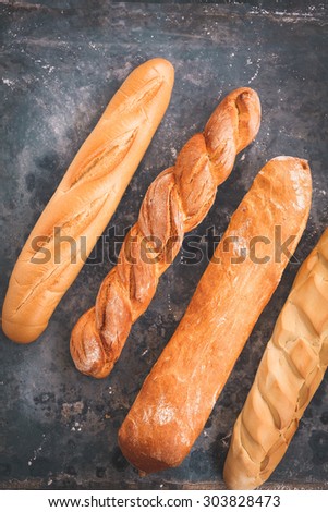 Various freshly baked french Baguettes over on a rustic blue background. Four different baguettes para sandwich from above.Country style