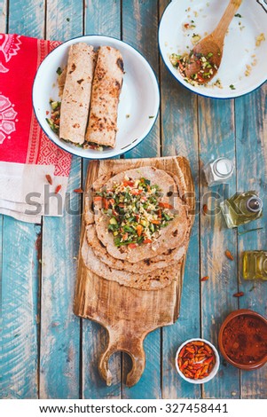 Making Homemade wholegrain flatbread with bulgur oriental tabbouleh salad, ready to prepare roll wrap sandwich with various spices. Rustic image from above.