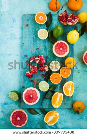 Mixed festive colorful tropical and citrus fruit sliced with leaves over light blue tabletop. Pastel rustic style.