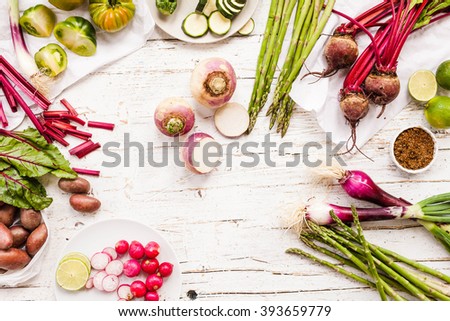Purple and green veggies and roots composition on a rustic white wooden table. Beetroot, red onion, radish, asparagus, green tomatoes, parsnip, parsley ready to prepare salad. detox and diet food.