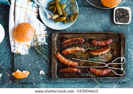 Grilled sausages in oven pan with pickled vegetables and bread bun. Homemade dinner party concept. country style. Typical cowboy food.