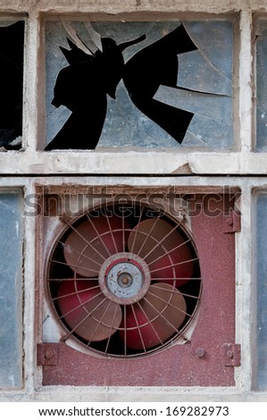 window with old fan and broken glass