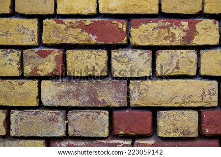 a ragged red and yellow painted brick wall with big gaps between bricks