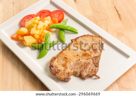 Pork chop with new potatoes peas and carrots and tomato