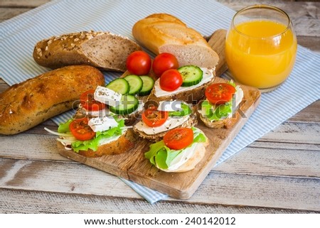 Small bites for breakfast with vegetables, cheese and orange juice, on wooden table