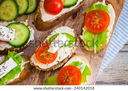 Small bites for breakfast with vegetables and cheese, on wooden table, top view and closeup