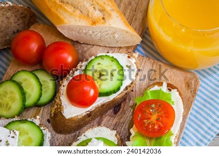 Small bites for breakfast with vegetables, cheese and orange juice, on wooden table, top view and closeup