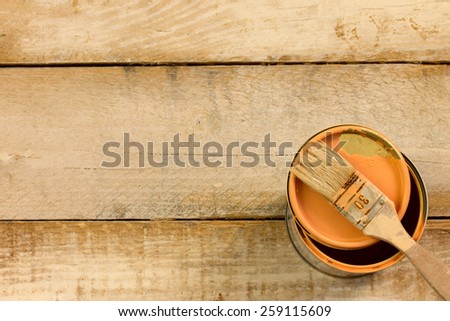 orange paint with paint brush over  wooden background