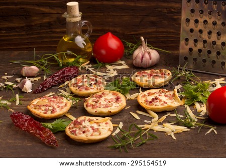 mini pizzas with ingredients over a dark wooden table
