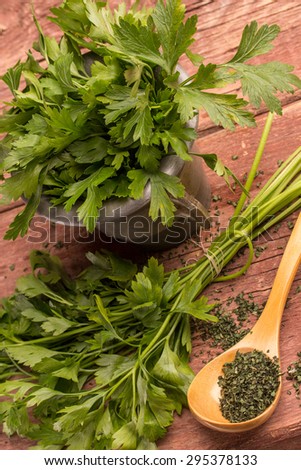 fresh and dried parsley on a wooden surface