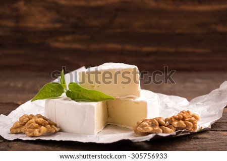 Sliced round camembert cheese traditional milk creamy dairy product on vintage wooden table.