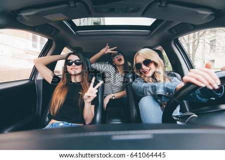 Group of friends having fun on the car. Singing and laughing in the city