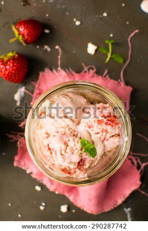 Strawberry ice cream with meringue in a jar on a dark background