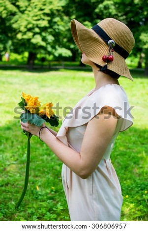 dark-haired woman in a bright pink dress and a straw hat with a bouquet of flowers zucchini