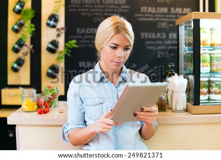 Owner of small restaurant holding a digital tablet