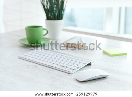 Office table with notepad, computer, flower and coffee cup